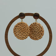 Boho Rattan Circular Earrings ion a circular wooden stand on a gray background.  