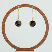 Golden Leverback Earrings on a circular wooden stand on a white background.  