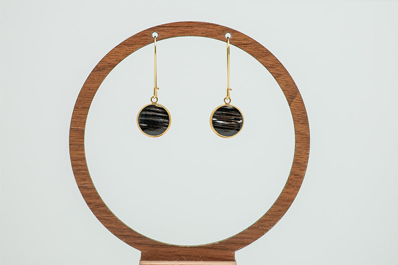 Golden Leverback Earrings on a circular wooden stand on a white background.  