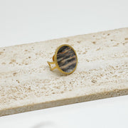 A Gold Statement Ring on white marble on a white background.