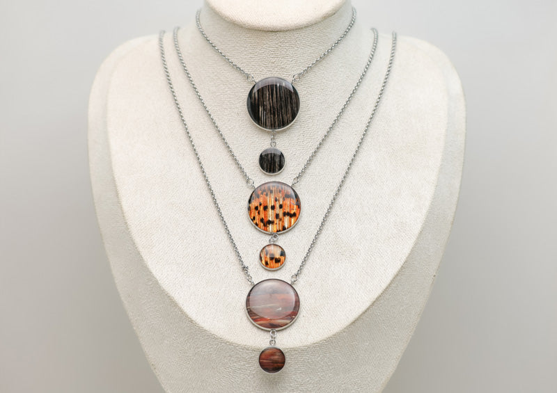 Three Adjustable Statement Necklaces on a cream necklace display bust. 