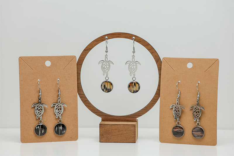 Three pairs of Silver Turtle Dangles on stands on a white background.