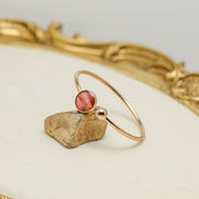 A Rose Gold Cuff on a rock on a white background with gold frame.