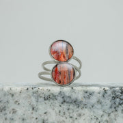 A Silver Double Pendant Statement Ring on black and white marble on a white background.