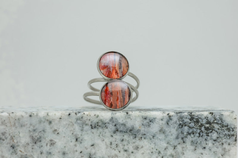 A Silver Double Pendant Statement Ring on black and white marble on a white background.
