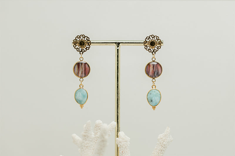 Larimar Mandala Drop Earrings on a gold stand on a white background with white coral at the bottom of the image. 