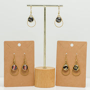 Three pairs of Small Golden Teardrop Earrings on stands on a white background.  
