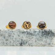 Three Gold Adjustable Rings on black and white marble on a white background.