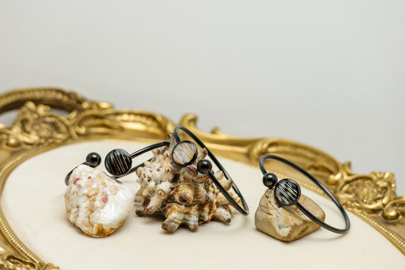 Three Black Cuffs on shells on a white background with a gold frame. 