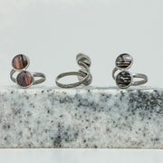 Three Silver Double Pendant Adjustable Rings on black and white marble on a white background.