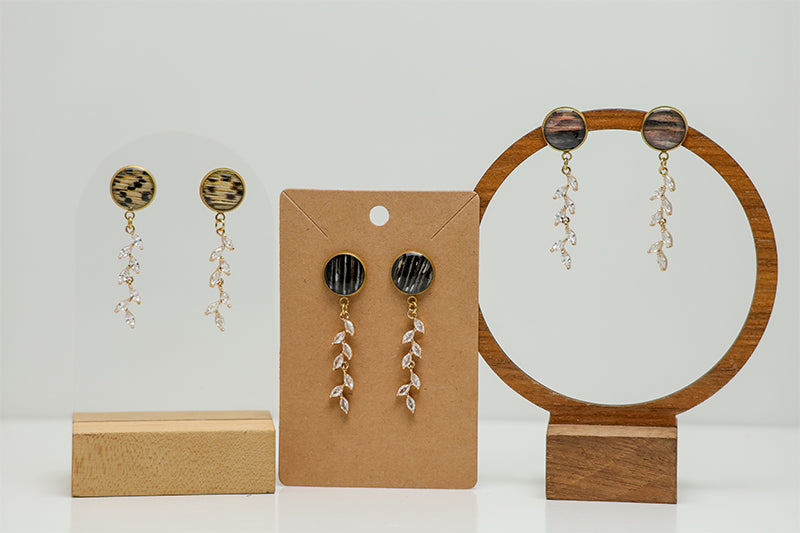 Three pairs of Cascading Diamond Earrings on stands on a white background.  