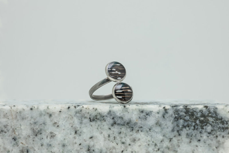 A Silver Double Pendant Adjustable Ring on black and white marble on a white background.