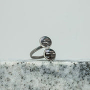 A Silver Double Pendant Adjustable Ring on black and white marble on a white background.