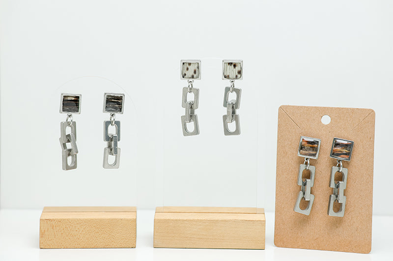 Three pairs of Chain Link Earrings on stands on a white background. 