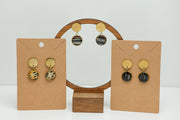 Three pairs of Round Golden Earrings on stands on a white background.  
