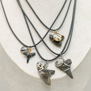 Four Shark Tooth Necklaces on a cream necklace display bust. 