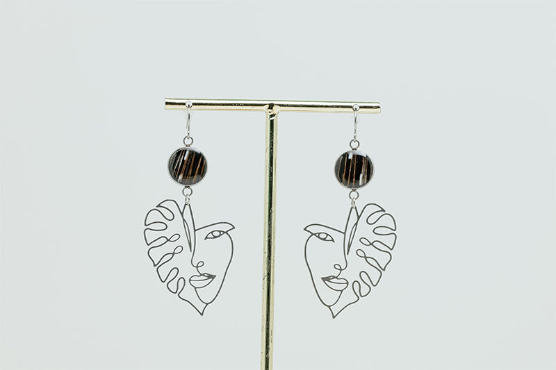 Into the Jungle Earrings on a gold stand on a white background.