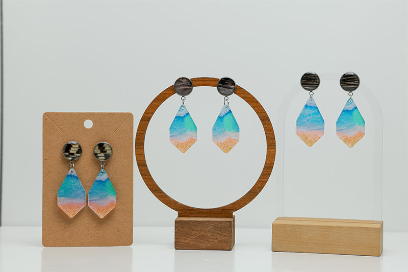 Three pairs of Seas the Day Earrings on stands on a white background. 