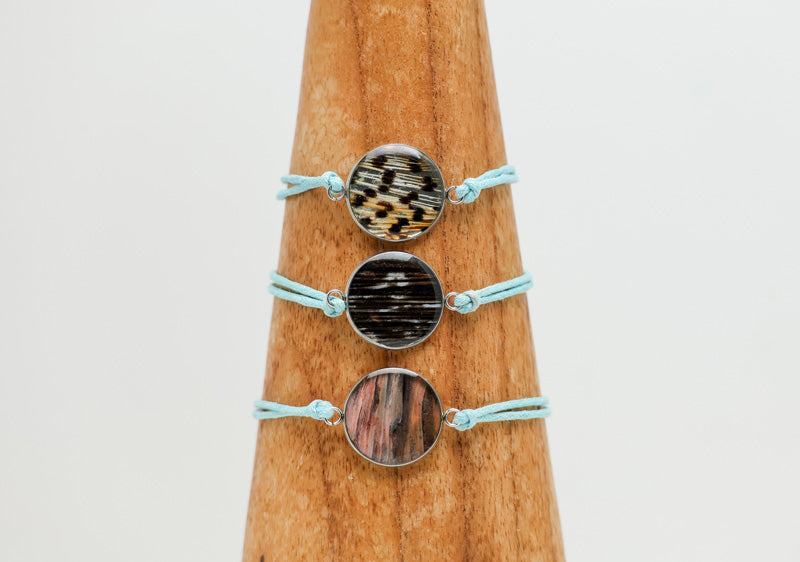 Three Blue Cord Bracelet on a wooden triangle on a white background. 