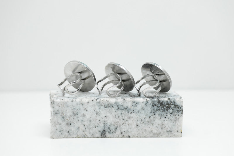 Three Silver Statement Rings on black and white marble on a white background.