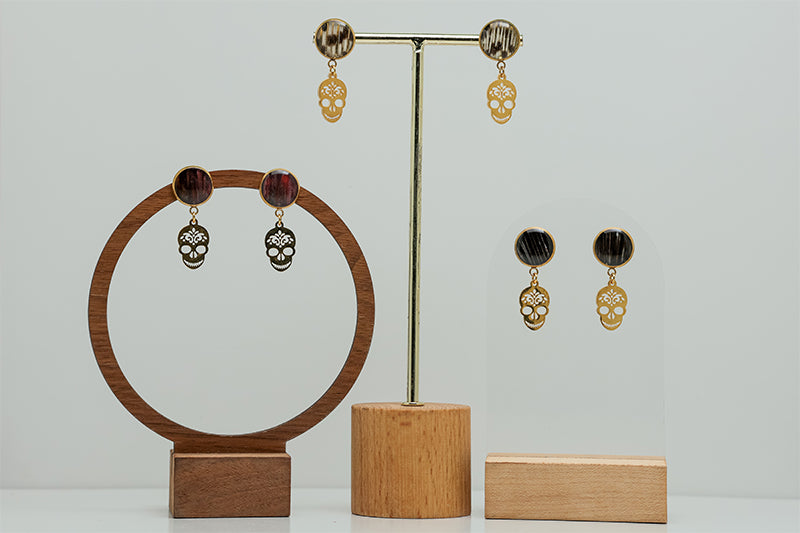 Three pairs of Sugar Skull Earrings on stands on a white background.  