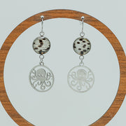 Octopus Earrings on a circular wooden stand on a white background. 