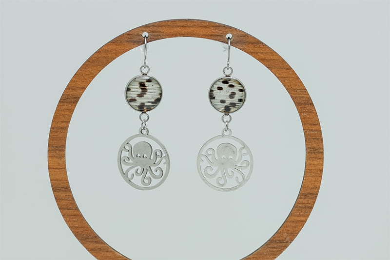 Octopus Earrings on a circular wooden stand on a white background. 