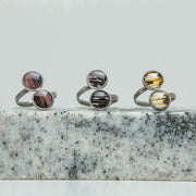 Three Silver Double Pendant Adjustable Rings on black and white marble on a white background.