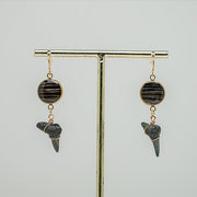 Shark Tooth Gold Dangles Earrings on gold stand on a white background. 