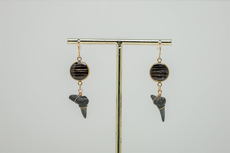 Shark Tooth Gold Dangles Earrings on gold stand on a white background. 