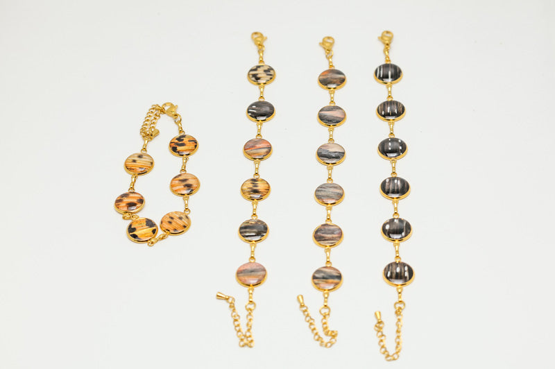 Four gold lionfish fin tennis bracelets with six 12mm round resin charms in tail, pectoral, pelvic and mixed fin variants with adjustable clasp on white background