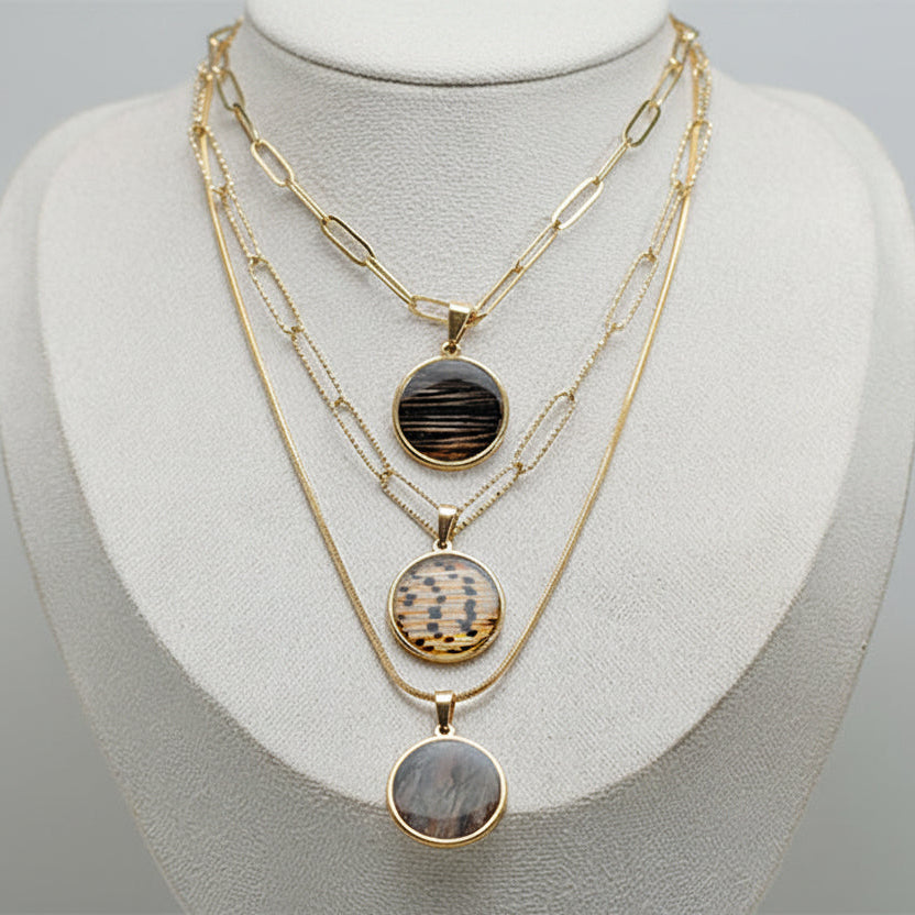 Large gold layered necklace with three lionfish fin resin pendants on paperclip and dainty chain styles displayed on white jewelry bust