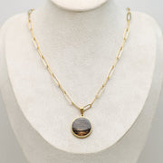Large gold lionfish fin pendant necklace with paperclip chain and 20mm round resin pendant on cream jewelry bust
