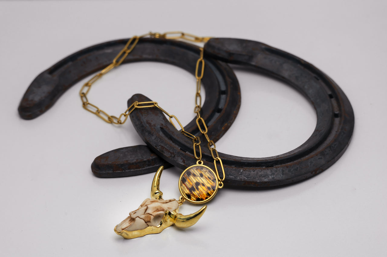 Close-up of lionfish fin pendant with longhorn cattle pendant on Rpaperclip necklace siplayed on two horseshoes