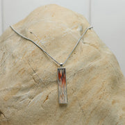 Silver Bar Necklace with grey and red pectoral fin displayed on natural stone