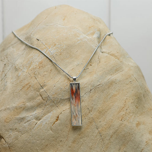 Silver Bar Necklace with grey and red pectoral fin displayed on natural stone