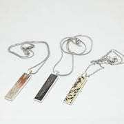 Three Silver Bar Necklaces on a white background.